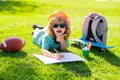 Little painter draw pictures outdoor. Clever school boy doing homework, writing on copy book in green grass of park Royalty Free Stock Photo