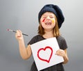 Little painter girl with a drawn heart isolated on grey