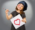 Little painter girl with a drwan heart isolated on grey