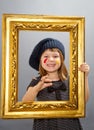 Little painter girl looking through a vintage picture frame