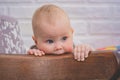 Little pensive child sitting in a vintage brown chair biting the back of the chair Royalty Free Stock Photo