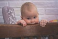 Little pensive child sitting in a vintage brown chair biting the back of the chair Royalty Free Stock Photo