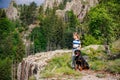 Girl with stands next to her dog of the Rottweiler breed on a peak with vegetation against the cloudy sky Royalty Free Stock Photo