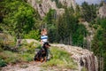 Girl with stands next to her dog of the Rottweiler breed on a peak with vegetation against the cloudy sky Royalty Free Stock Photo