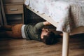 Little, pensive, two years old boy sitting under the bed and playing with toy children& x27;s car Royalty Free Stock Photo