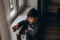 Little, pensive, two years old boy sitting by the window and playing with toy children& x27;s car Royalty Free Stock Photo
