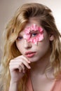 Tender blue-eyed woman having little pink petals around her eye