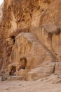 Bedouin sitting on sandstone near a stairs carved on rocks