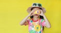 Little photographer taking photo by toy camera. Child tourists in floral pattern summer dress and hat with sunglasses isolated on