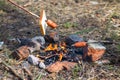 Little picnic with family. Sausages and bread are fried over a small fire. Grilling sausages over a campfire in the forest.