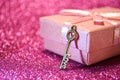 Little pink gift box with ribbon bow and golden love key on abstract glitter bokeh Royalty Free Stock Photo