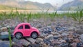 Little pink toy car on nature background. Summer vacation, travel concept. Royalty Free Stock Photo