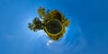 little planet projection panorama of sunny autumnal mowed meadow and yellow forest on its edges with blue sky and clouds