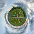 Little planet view of village houses and distant green cultivated agricultural fields with growing crops on bright