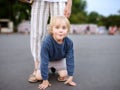 Little playful boy having fun during walking with his mother. Child fooling around warm summer evening in public park Royalty Free Stock Photo