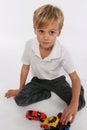 A little playful boy playing with car toys on his knees