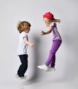 Little positive blond baby girl and boy sister and brother in stylish casual clothing and accessories jumping and having fun Royalty Free Stock Photo