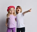 Little positive blond baby girl and boy in stylish casual clothing and accessories standing, hugging each other feeling cheerful Royalty Free Stock Photo