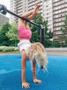 little preschool blonde Caucasian girl hanging upside down on pullup bar on playground Royalty Free Stock Photo