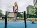 Little preschool blonde Caucasian girl hanging upside down on pullup bar on playground