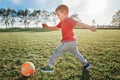 Little preschool Caucasian boy playing soccer football on playground outside. Kid kicking hitting ball. Happy authentic candid Royalty Free Stock Photo