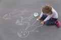 Little preschool caucasian girl drawing a happy family with chalks on the pavement