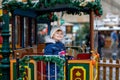 Little preschool girl on a carousel train at Christmas funfair or market, outdoors. Happy child having fun. Traditional Royalty Free Stock Photo