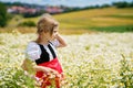 Little preschool girl in daisy flower field. Cute happy child in red riding hood dress play outdoor on blossom flowering Royalty Free Stock Photo