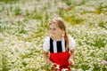 Little preschool girl in daisy flower field. Cute happy child in red riding hood dress play outdoor on blossom flowering Royalty Free Stock Photo