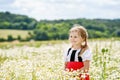 Little preschool girl in daisy flower field. Cute happy child in red riding hood dress play outdoor on blossom flowering Royalty Free Stock Photo