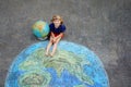 Little preschool girl with earth globe painting with colorful chalks on ground. Positive toddler child. Happy earth day Royalty Free Stock Photo