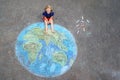 Little preschool girl with earth globe painting with colorful chalks on ground. Positive toddler child. Happy earth day concept. Royalty Free Stock Photo