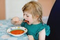 Little preschool girl eating healthy vegetable tomato soup for lunch. Cute happy child taking food at home or nursery Royalty Free Stock Photo