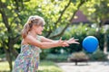 Little preschool girl with eyeglasses playing with ball outdoors. Happy smiling child catching and throwing, laughing Royalty Free Stock Photo