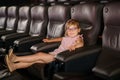 Little preschool girl with glasses watching cartoon movie in cinema and eating popcorn. Happy excited child. Activity Royalty Free Stock Photo
