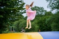 Little preschool girl jumping on trampoline. Happy funny toddler child having fun with outdoor activity in summer Royalty Free Stock Photo