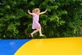 Little preschool girl jumping on trampoline. Happy funny toddler child having fun with outdoor activity in summer Royalty Free Stock Photo