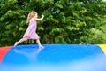 Little preschool girl jumping on trampoline. Happy funny toddler child having fun with outdoor activity in summer Royalty Free Stock Photo
