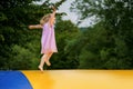 Little preschool girl jumping on trampoline. Happy funny toddler child having fun with outdoor activity in summer