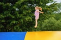 Little preschool girl jumping on trampoline. Happy funny toddler child having fun with outdoor activity in summer Royalty Free Stock Photo