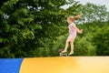 Little preschool girl jumping on trampoline. Happy funny toddler child having fun with outdoor activity in summer Royalty Free Stock Photo