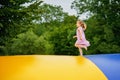 Little preschool girl jumping on trampoline. Happy funny toddler child having fun with outdoor activity in summer Royalty Free Stock Photo