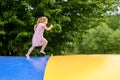 Little preschool girl jumping on trampoline. Happy funny toddler child having fun with outdoor activity in summer