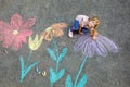 Little preschool girl painting with colorful chalks flowers on ground on backyard. Positive happy toddler child drawing Royalty Free Stock Photo