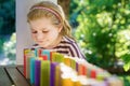 Little preschool girl playing board game with colorful bricks domino. Happy child build tower of wooden blocks Royalty Free Stock Photo