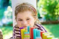 Little preschool girl playing board game with colorful bricks domino. Happy child build tower of wooden blocks Royalty Free Stock Photo