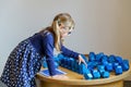 Little preschool girl playing with large blue logical objects cubes in children museum. Happy concentrated child with