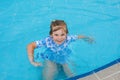 Little preschool girl playing in outdoor swimming pool in hotel resort. Child learning to swim in outdoor pool Royalty Free Stock Photo