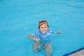 Little preschool girl playing in outdoor swimming pool in hotel resort. Child learning to swim in outdoor pool Royalty Free Stock Photo