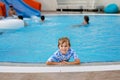 Little preschool girl playing in outdoor swimming pool in hotel resort. Child learning to swim in outdoor pool Royalty Free Stock Photo